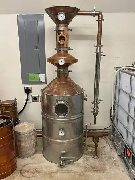 Copper still head installed above a stainless steel vessel